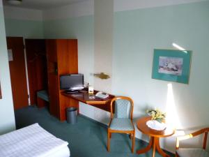Habitación de hotel con escritorio, cama y silla en Hotel Brandenburg en Königs Wusterhausen
