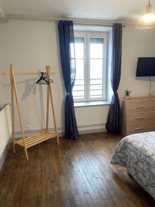 a bedroom with blue curtains and a bed and a window at Appartement meublé - 2 Chambres in Montbard