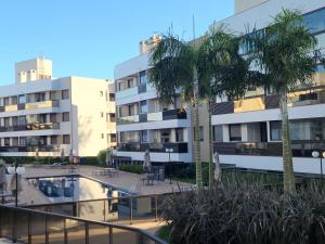 a building with a swimming pool and a palm tree at Mar de ensueños in Florianópolis