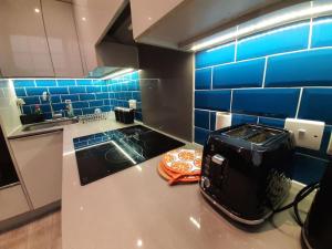 a kitchen with a counter with a toaster and blue tiles at Super Central 2bed Central Reading - free parking in Reading