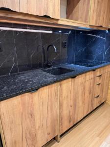 a kitchen with a sink and black marble counter top at Mountain Lodge T3 Duplex Abrigo do Lobo in Penhas da Saúde +71 photos