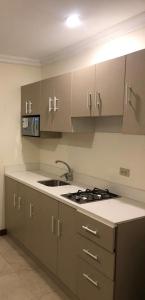 a kitchen with a sink and a stove and cabinets at DORAL SUITE ¡CERCA DEL AEROPUERTO! in Guayaquil