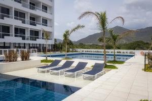 a swimming pool with lounge chairs and a building at Aparta suite Playa Bello Horizonte Santa Marta in Santa Marta