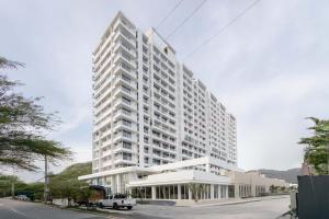 a large white building with a car parked in front of it at Aparta suite Playa Bello Horizonte Santa Marta in Santa Marta