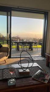a glass of wine on a table in a room at Ramarama retreat, farm views, spa bath & deer in Ramarama