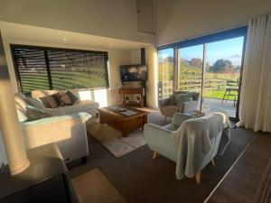a living room with a couch and chairs and a large window at Ramarama retreat, farm views, spa bath & deer in Ramarama