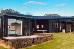 a black house with a large window in a yard at Ramarama retreat, farm views, spa bath & deer in Ramarama