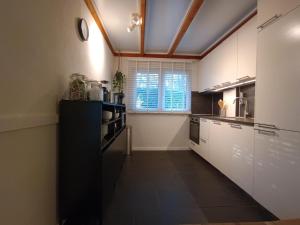 a large kitchen with white cabinets and a window at Boshuis Rosanne in Meijel