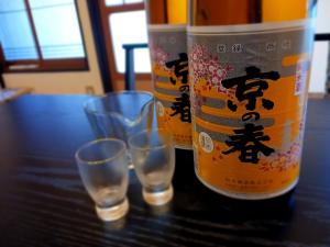 zwei Flaschen Wein und drei Gläser auf einem Tisch in der Unterkunft もりたさんち in Taitsuri-shima