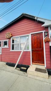 a red house with a red door and a sign at Hostal Vista al Mar in Puerto Natales