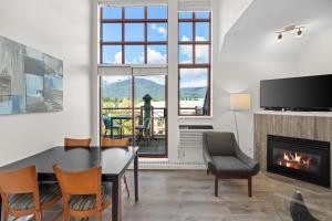 a living room with a dining room table and a fireplace at Alpenglow Lodge Junior Penthouse by MVA in Whistler