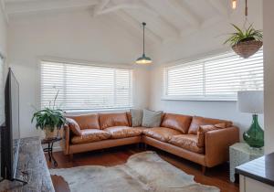 a living room with a brown leather couch at Sunset House - Oceanstays in Yamba