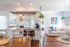 a kitchen and living room with a couch and a table at Sunset House - Oceanstays in Yamba