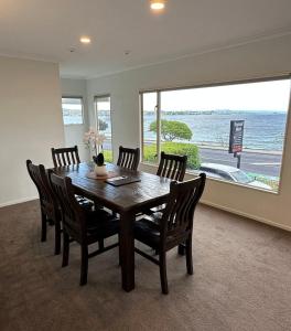 a dining room with a table and chairs and a large window at Baycourt Lakefront Motel in Taupo