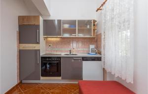 una piccola cucina con elettrodomestici in acciaio inossidabile e uno sgabello rosso di Holiday Apartment Betiga 03 a Barbariga