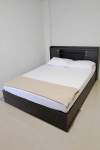 a bed with a black frame and white sheets at Na Nont Place in Bangkok