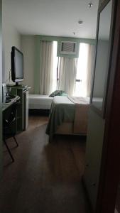 a bedroom with a bed and a tv and a window at comfort hotel 413 anfitriã in Taguatinga