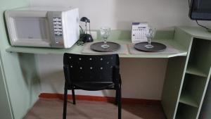 een bureau met een magnetron en twee glazen erop bij comfort hotel 413 anfitriã in Taguatinga +4 foto's