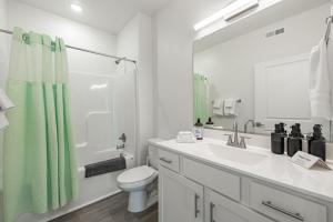 a white bathroom with a green shower curtain and a toilet at Tourist Home of Richmond - Church Hill North Apt01 in Richmond +7 photos