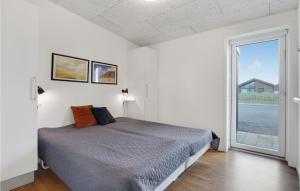 Un dormitorio con una cama y una ventana grande. en Holiday Home Ringkøbing 57, en Søndervig