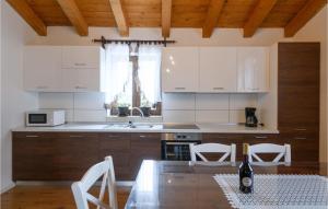 kuchnia z białymi szafkami, stołem i krzesłami w obiekcie Stunning Home In Trosti w mieście Rojnići