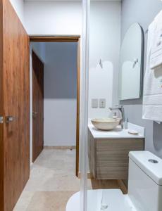 a white bathroom with a sink and a toilet at Apartment with Private Jacuzzi, Rooftop Pools & Free beach club in Tulum