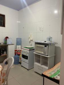 a kitchen with a stove and a microwave at Casa confortável a 5 minutos da Praia do Forte a pé in Cabo Frio