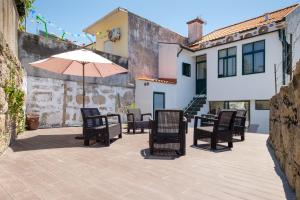 a patio with tables and chairs and an umbrella at Entire House with 4 Master Suites & Backyard - Central Location in Vila Nova de Gaia