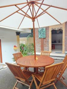 a wooden table with chairs and an umbrella at Lavista Guesthouse in Ubud