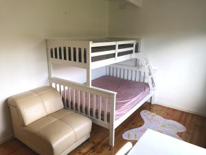 a white bunk bed with a chair and a couch at Rye Holiday Getaway BYO Linen and Towels 750m walk to Beach in Rye +11 photos