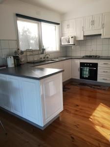 a kitchen with white cabinets and a counter top at Rye Holiday Getaway BYO Linen and Towels 750m walk to Beach in Rye
