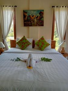 a white bed with a stuffed animal on it at Lavista Guesthouse in Ubud