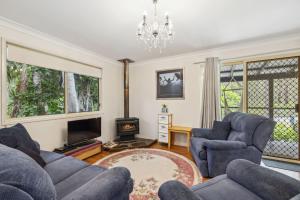 un salon avec deux chaises bleues et une télévision dans l'établissement Beach Cottage, à Woolgoolga