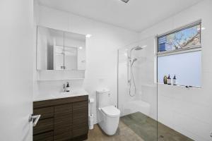 a white bathroom with a toilet and a shower at Aireys Bush Retreat in Aireys Inlet +7 photos