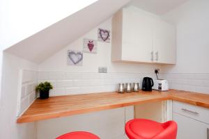 a kitchen with white cabinets and a red chair at Hope Deluxe King Bedroom Manchester in Middleton +47 photos