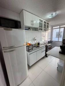 una cucina con mobili bianchi e un frigorifero di Duplex Cobertura Premium a Feira de Santana