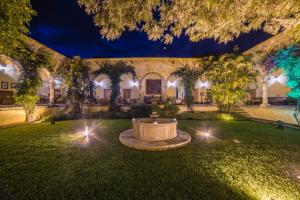un patio con una fuente y árboles por la noche en Hacienda Labor de Rivera Hotel Boutique, en Teuchitlán