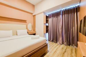 a small room with a bed and a window at Homey and Modern 2BR at Casa de Parco Apartment By Travelio in Tangerang +7 photos