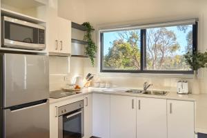 a kitchen with white cabinets and a window at Gumleaf in Coles Bay