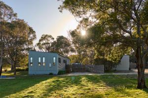 a blue house in a park with a tree at Gumleaf in Coles Bay