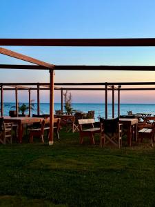 a group of tables and chairs with the ocean in the background at LUXE COASTAL RETREAT Apartment in Alexandroupoli
