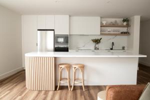 a kitchen with a white counter and stools at Apartment Two - Apartments on Gavan in Bright
