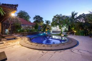 a swimming pool in a yard with a patio at Beach Front Hotel Danau Tamblingan St Sanur Bali in Sanur