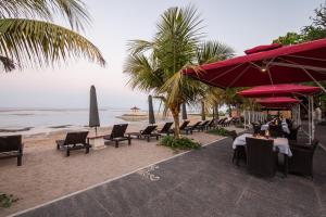 a beach with chairs and tables and umbrellas and the ocean at Beach Front Hotel Danau Tamblingan St Sanur Bali in Sanur