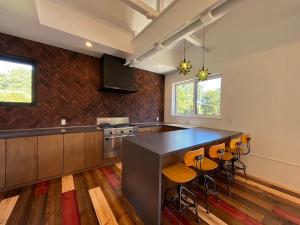a kitchen with a black counter top and stools at Straddie House Niseko Village in Niseko