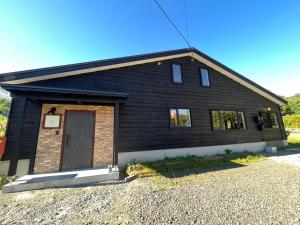a black house with a door on the side of it at Straddie House Niseko Village in Niseko