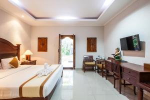 a bedroom with a bed and a desk and a tv at Beach Front Hotel Danau Tamblingan St Sanur Bali in Sanur