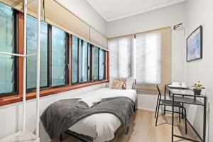 a bedroom with a bed and a desk and windows at Cozy Private Single Room in Carramar - Nearby Station & Shops - Shared Bathroom in Sydney