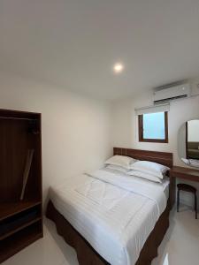 a bedroom with a white bed and a mirror at Sampai Living Tugu in Yogyakarta