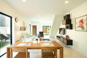 a dining room and living room with a wooden table at Krabi Private Pool Villa 2 by Belcarra Spaces in Ban Khlong Haeng